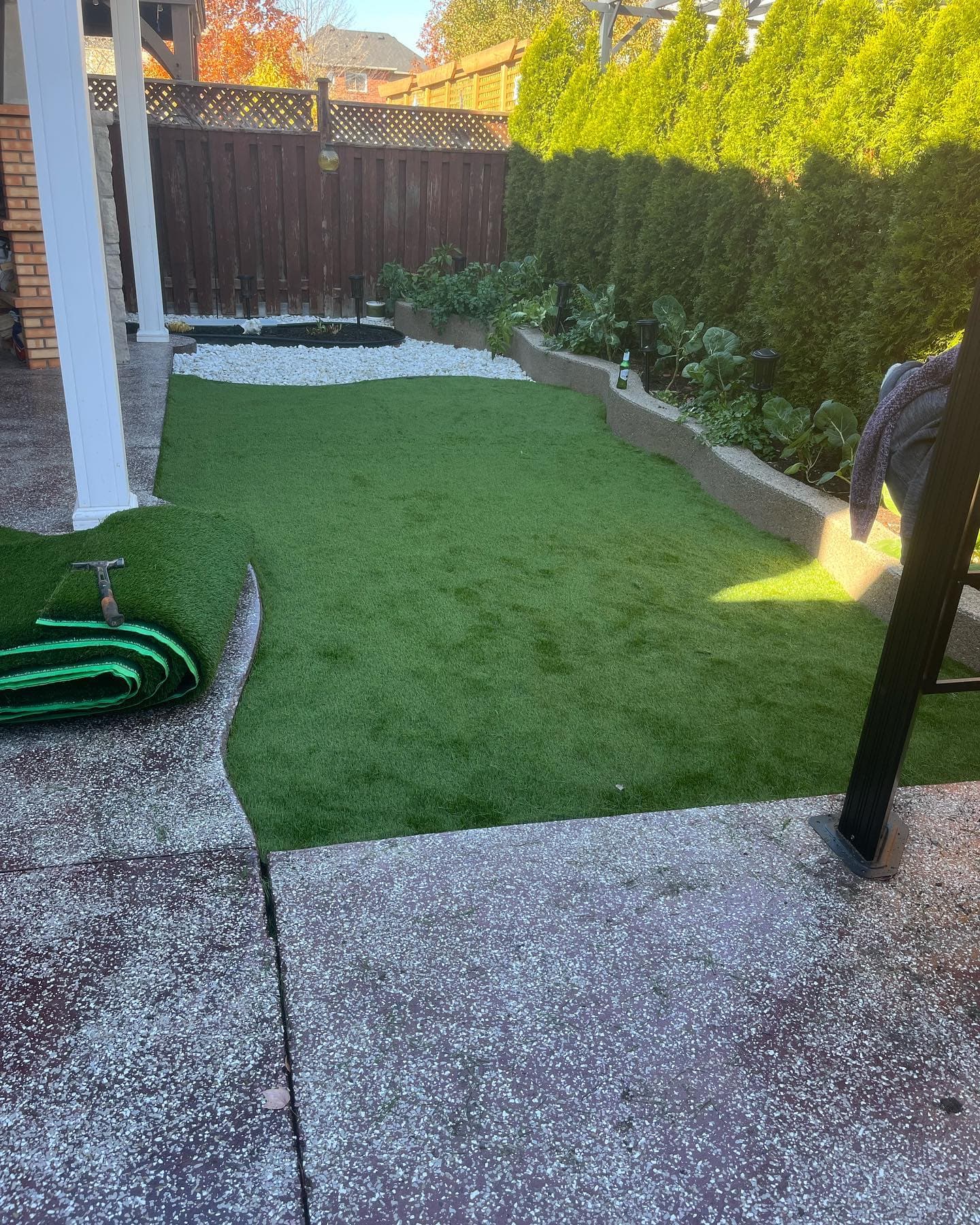Finished artificial turf lawn alongside a patio with raised garden bed