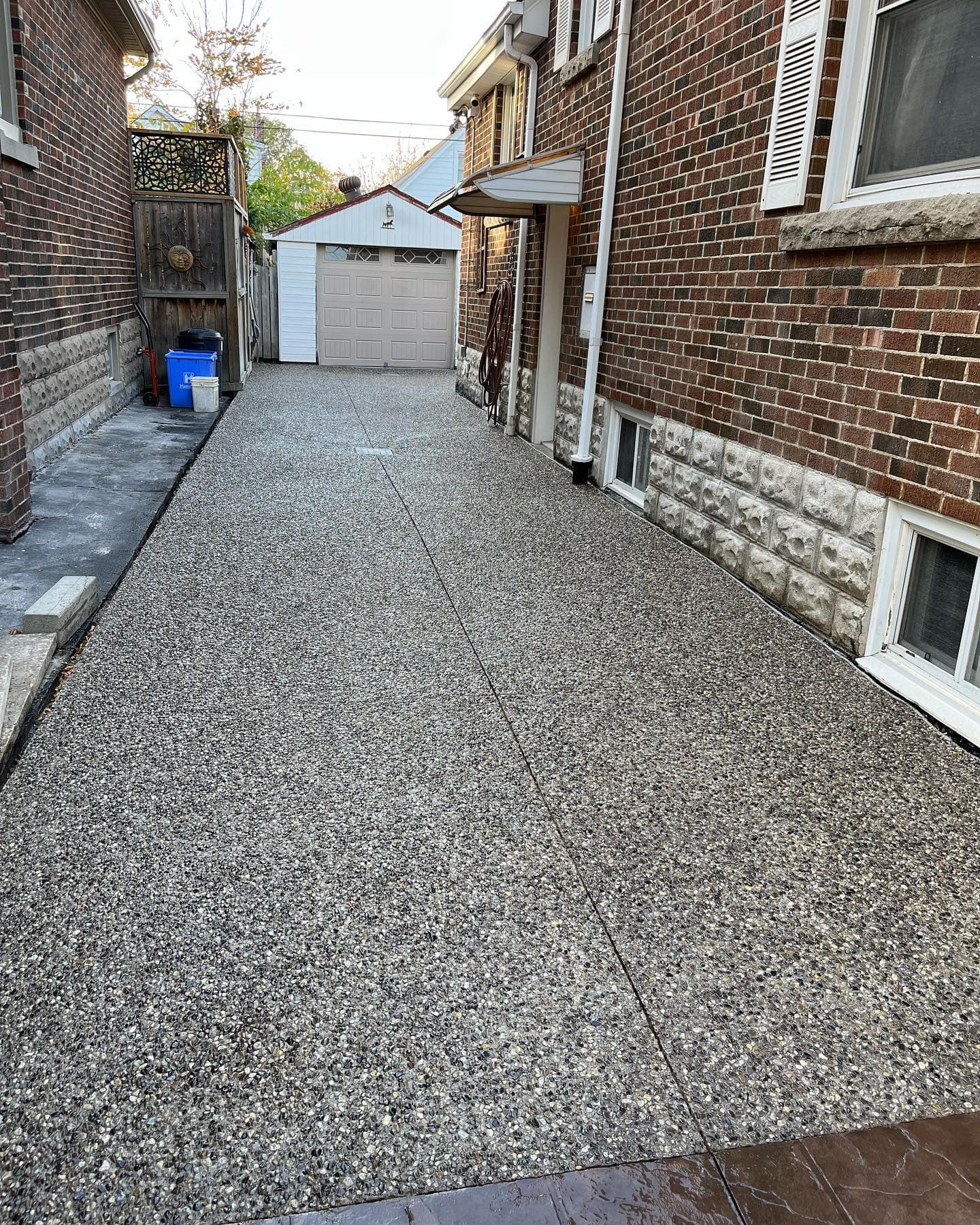 Exposed-aggregate concrete driveway between two houses